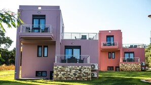 Un edificio moderno de dos plantas con balcones, detalles de piedra y mobiliario exterior.