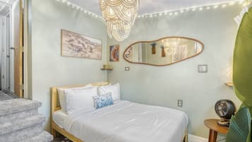 Un dormitorio con una cama, una araña, un espejo y obras de arte en la pared.