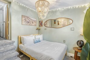 Ein Schlafzimmer mit einem Bett, einer Chandelier, einem Spiegel und Kunstwerken an der Wand.