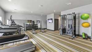 Ett gym med löpband, vikter och träningsbollar.