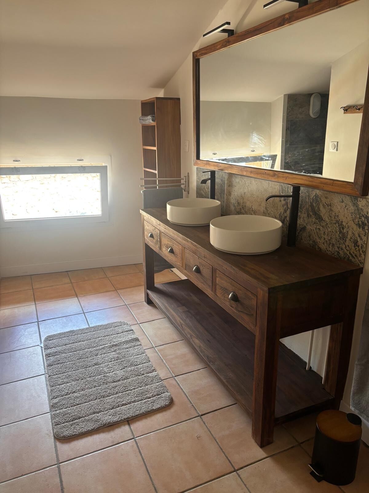 A bathroom with two sinks, a large mirror, and a window.