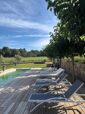 A wooden deck with lounge chairs and a pool. - NEW! Large Modern Home on a Vineyard Estate - Pool, Nature, Sleeps 14 (Puisserguier)