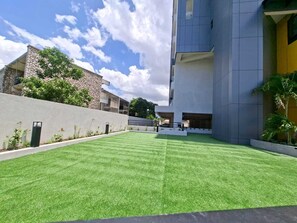 A modern building with a flat roof, a stone facade, and a well-maintained lawn. - Heart of New KGN/Gated/TV/Wifi/AC/Pool/Embassies (Kingston)