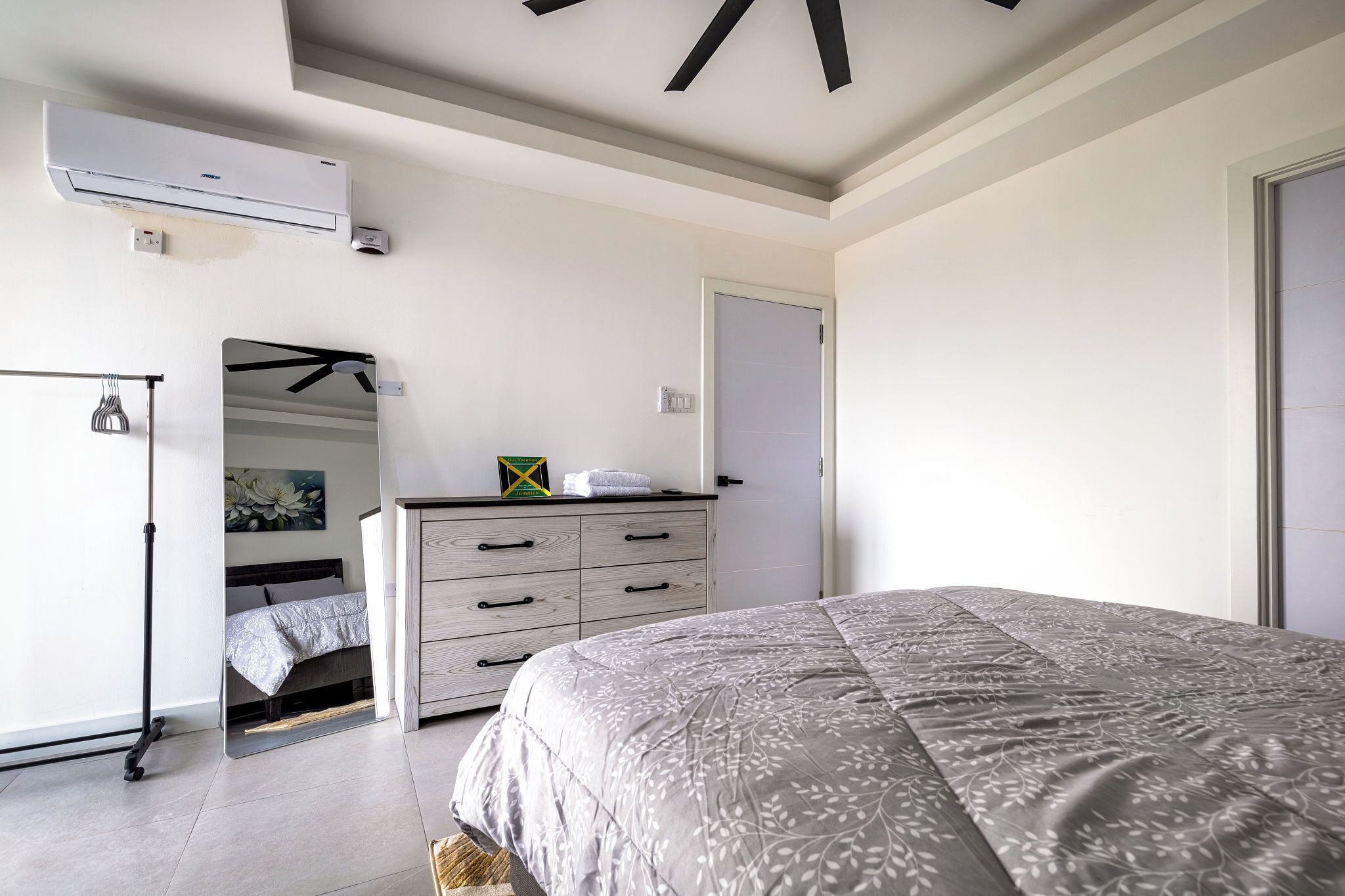 Quarto com cama, cômoda e ar-condicionado.