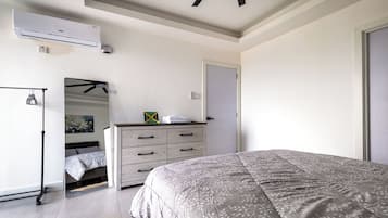 Quarto com cama, cômoda e ar-condicionado.