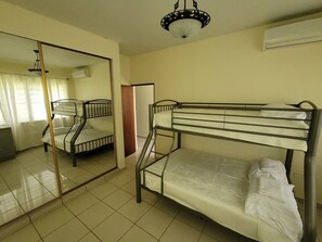 A room with bunk beds, a large mirror, and an air conditioning unit.