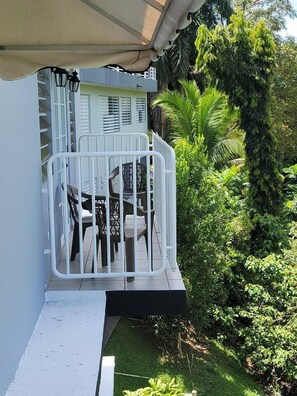 Ein Balkon mit weißer Brüstung, einem Tisch und Stühlen.