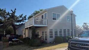 A two-story house with a balcony, a barbecue grill, and a truck parked in front.