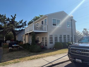A two-story house with a balcony, a barbecue grill, and a truck parked in front.