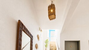 Una escalera con un espejo, un tapete tejido, una planta en maceta y una puerta.
