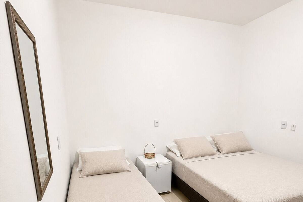 Ett sovrum med två sängar, ett sängbord och en spegel som är monterad på väggen.
