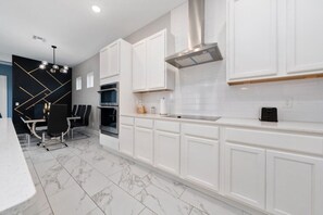A modern kitchen with white cabinets, a marble floor, and a built-in oven. - Beautiful &Relaxing 5BR Home w/Private Pool (62EW) (Kissimmee)