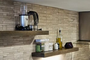 Eine Küche mit Backsteinrückwand, einem Mixer auf der oberen Ablage und verschiedenen Küchenutensilien auf der unteren Ablage.