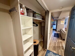 Een gang die uitkomt op een woonruimte met een houten vloer, een deur en een uitzicht op een kamer met een bank en een raam.
