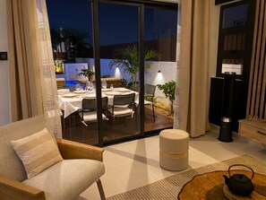 A modern living room with a sofa, ottoman, and a table with a teapot. - Villa Moony | Private Pool, Rooftop, and Wellness Villa in Mauritius (Trou aux Biches)