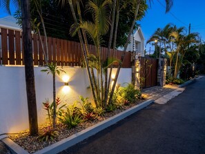 A residential area with a white wall, wooden fence, and a gated entrance. - Villa Moony | Private Pool, Rooftop, and Wellness Villa in Mauritius (Trou aux Biches)