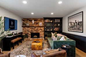 Ein Wohnzimmer mit Kamin aus Ziegelsteinen, einem grünen Sofa, einem Couchtisch und einem Bücherregal.