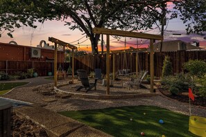 Ein Garten mit Schaukel, Sitzgelegenheit und einer Holz-Pergola.