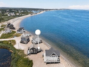 Vista aérea de una zona costera con casas, una playa y un faro.