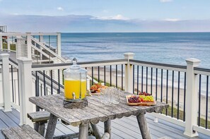 Eine Holzterrasse mit Frühstückstisch, mit Blick auf den Ozean.