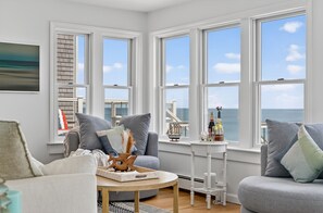 Ein Zimmer mit Meerblick, eine Sitzecke, ein Tisch mit Tablett und ein kleiner weißer Tisch mit Dekoration.