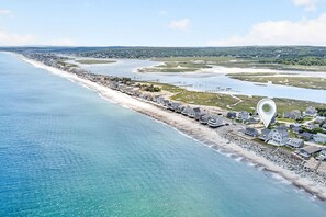 Eine Luftaufnahme einer Küstenstadt mit Strand, Häusern und einem Steg.