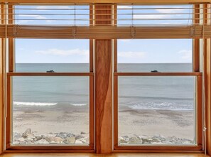 Ein großes Fenster mit Blick auf Strand und Meer.