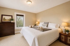 A bedroom with a large bed, a dresser, a window, and two bedside lamps.