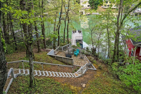 A wooden deck with a staircase leading to a viewing platform, surrounded by trees and overlooking a body of water.