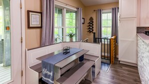 Une cuisine équipée d’un banc, d’une table à manger et offrant une vue sur l’extérieur.