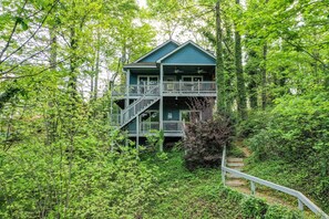 Eine zweistöckige Holzhütte mit Balkon, umgeben von dichtem Wald.