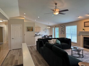 A modern living room with a dark green sofa, a small round coffee table, and a fireplace.