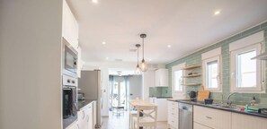 Een moderne keuken met witte kasten, een houten aanrecht en een hanglamp.