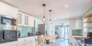 Eine moderne Küche mit Mikrowelle, Backofen und Kühlschrank. Es gibt einen Essbereich mit Tisch und Stühlen.