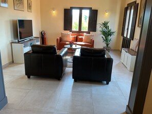 A living room with a sofa set, a coffee table, a television, and a potted plant.
