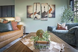 Een woonkamer met een salontafel, twee banken en een muur met kunstwerken over golf.