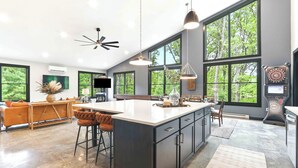 Une cuisine spacieuse avec un grand îlot central, des tabourets de bar et un ventilateur de plafond.