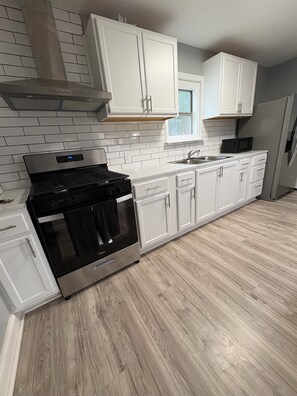 A modern kitchen with white cabinets, a stainless steel stove, and a microwave.