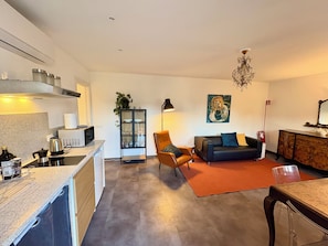 A modern living room with a sofa, a coffee table, a dining table, and a kitchen area with a stove and cabinets. - "C7 Balcony Railing" — New, with a balcony in Omegna (Omegna)