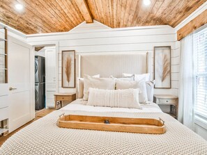 A bedroom with a wooden ceiling, a bed with white bedding, a wooden tray, and a framed picture on the wall. - The Tenley -Boutique Cottage in Tech Terrace Walk to TTU, J&B & Goodline (Lubbock)