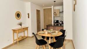 Un comedor con una mesa redonda, sillas negras, una mesita de madera y una lámpara colgante.