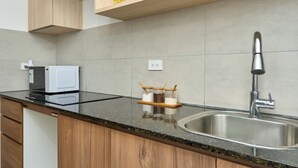 Una cocina con microondas, pileta y alacenas de madera.