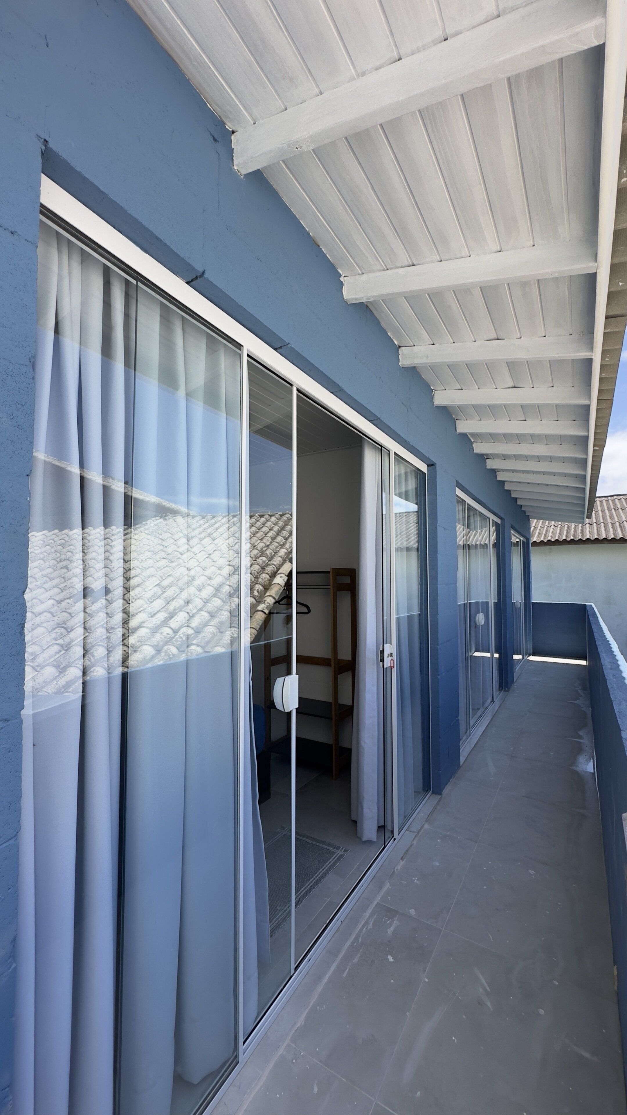 Un passadís amb portes corredisses de vidre, un balcó cobert i un sòl de rajola.