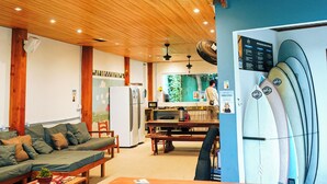 A wooden ceiling, a reception desk, a green sofa, a refrigerator, and surfboards. - Sea Wolf Surf Hostel - Campeche (Florianópolis)