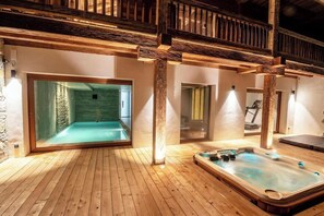 Ein Spa-Bereich mit Holzboden, einem Whirlpool und einem durch eine Glaswand abgetrennten Raum.