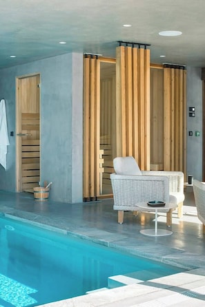 Ein moderner Poolbereich mit Liegestuhl, Holzwänden und einem Saunaraum.