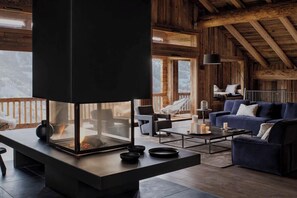 Ein modernes Interieur mit Kamin aus Glas, Holzbalken, einer Couch und einem Essbereich.