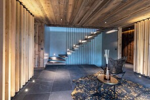 Ein modernes Interieur mit Holzboden, einer Wendeltreppe, einem Ledersofa und einem Teppich.