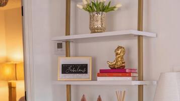 Ein weißes Regal mit goldenen Akzenten, das dekorative Gegenstände und Bücher beherbergt.
