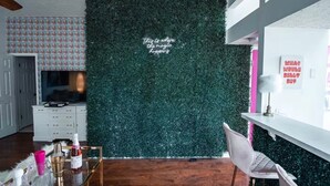 Una stanza con una parete verde, un armadietto bianco, una televisione e una sedia.